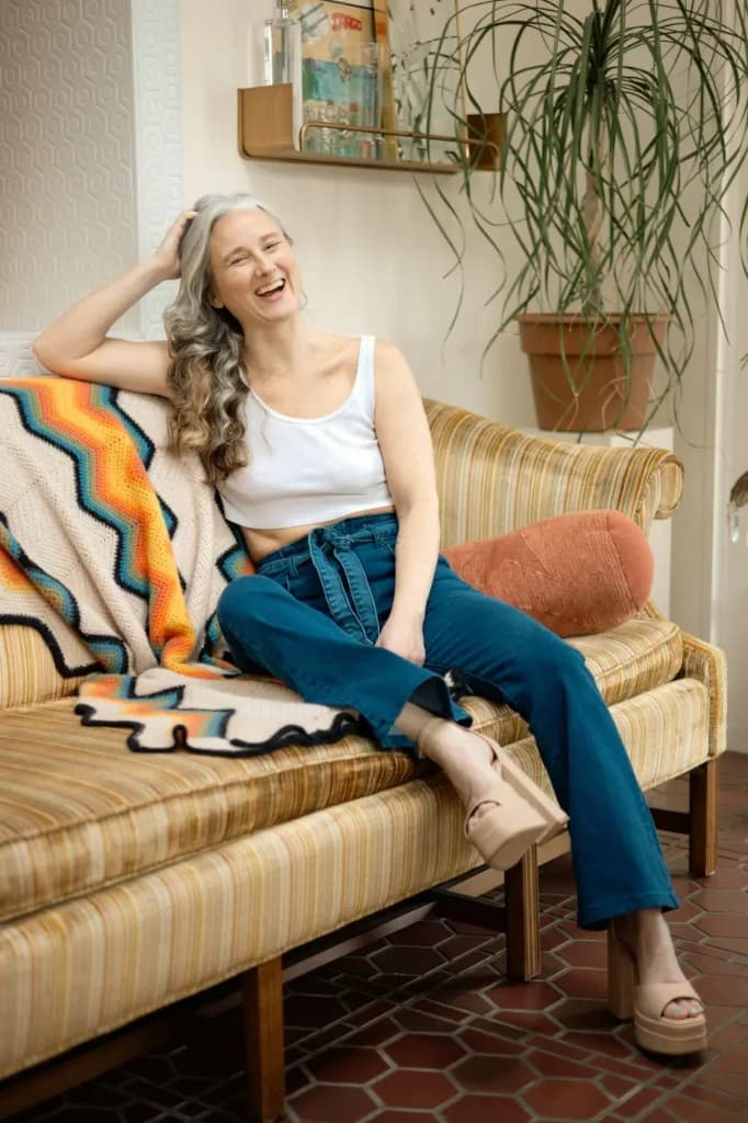 Sara Bryant laughing on a vintage sofa